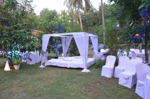 波戈马洛Raikar Guest House的一个带白色椅子和天篷的婚礼祭坛