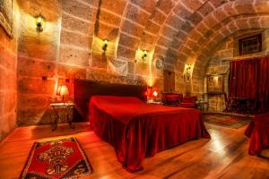 Guzelyurt卡帕多西亚古董吉维利洞穴酒店的一间石墙卧室,配有红色的床