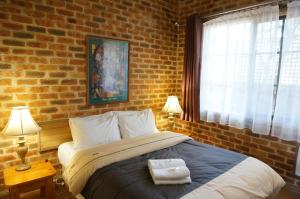 克兰伯恩红木公园汽车旅馆的一间卧室设有一张带砖墙的大床