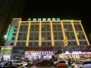 洛阳GreenTree Inn Luoyang Railway Station Wangfujing Wangcheng Park的一座大型建筑,前面有汽车停放