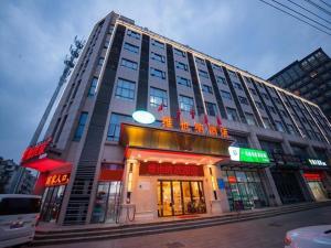 徐州Vienna Hotel Xuzhou Junsheng Plaza Benteng Avenue Metro Station的城市街道上一座大建筑,上面有标志