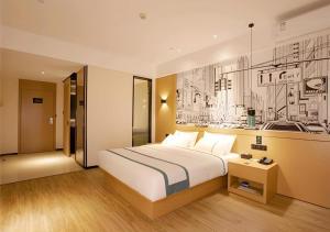 海口City Comfort Inn Haikou Zhongjie Road Walking Street的酒店客房设有一张床,墙上挂有绘画作品