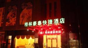 苏州GreenTree Inn Suzhou Wujiang Zhenze Town Zhennan Road Express Hotel的前面有 ⁇ 虹灯标志的建筑