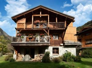 蒂涅CASA-Chalet Brizolée lake-view chalet in Tignes close to ski area的大型木屋,阳台上种有鲜花