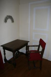 杜埃Château Hôtel de Warenghien的一张木桌和一个靠窗的红椅子