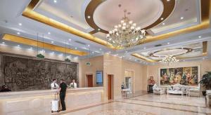 苏州Vienna Hotel Jiangsu Suzhou Wujiang Bus Passenger Station的一家酒店大厅,有一个人拿着行李箱