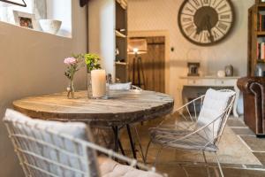 圣皮索内维尔埃洛尔迦农场住宿加早餐旅馆的一张带椅子的木桌和墙上的时钟