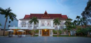 暹粒Sala Siem Reap Hotel的一座白色的大建筑,前面有棕榈树