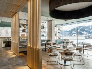 施伦斯Falkensteiner Family Hotel Montafon - The Leading Hotels of the World的餐厅配有桌椅,位于山脉的背景中。