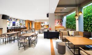 日惹黄星阿姆巴鲁克莫酒店的一间设有桌椅的餐厅,种植了植物