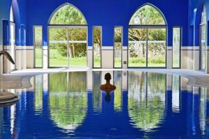 辛特拉辛特拉佩斯塔纳高尔夫SPA度假酒店的坐在游泳池里,坐在窗户间里的人