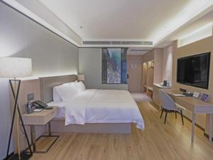 南通Gya Hotel Nantong Nanshang Lake Street Wanda Plaza的一间卧室配有一张床、一张书桌和一台电视