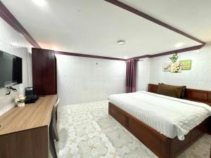 Phumĭ Kâmpóng KândalThe Cozy Corner-Budget Hotel的一间卧室配有一张床和一台平面电视