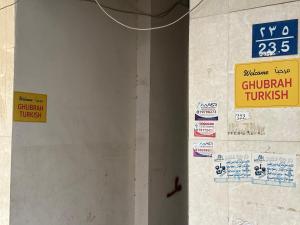 马斯喀特Ghubrah Turkish male hostel Muscat的建筑物上带有标志的墙