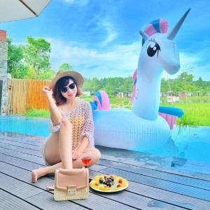 光邝FLAMIGO ĐẠI LẢI RESORT - Villa View Hồ的坐在游泳池旁的女人,拿着一盘食物