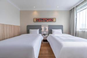 上海Hanting Hotel Shanghai Caohejing Yishan Road的配有白色床单的酒店客房内的两张床