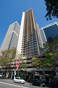 悉尼柏伟诗城市中心酒店的一座高大的建筑,前面有汽车停放