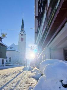 GontenAppenzeller Huus Löwen的一条雪 ⁇ 的街道,有教堂陡峭的陡峭壁和钟楼