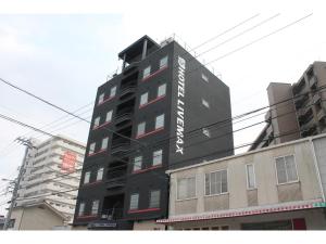 三原市HOTEL LiVEMAX Mihara Ekimae的一座黑色的建筑,旁边有一个标志