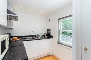伦敦Longridge Road Apartments By Viridian Apartments的厨房配有白色橱柜和窗户。
