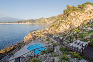 陶尔米纳UNAHOTELS Capotaormina的水边悬崖上的游泳池