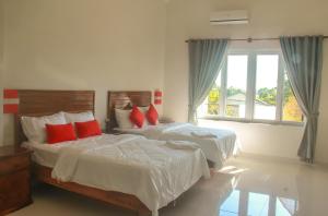 Bahal索卡旅馆的一间卧室配有两张带红色枕头的床和窗户。