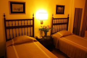波尔图总督酒店的一间卧室配有两张床、一盏灯和一部电话