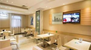 武汉City Comfort Inn Nanhu Jian'an Street Metro Station Baigang City的一间带桌椅的餐厅以及墙上的电视