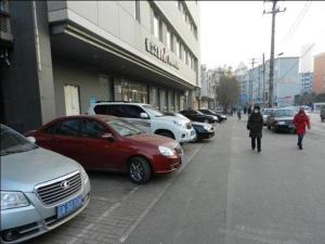 沈阳Jinjiang Inn Shenyang North Station的城市街道上一排停车的汽车