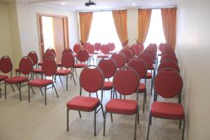 洛斯安赫莱斯Hotel Plaza Pinto的一间设有红色椅子和桌子及窗户的房间