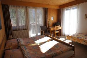 格林德尔瓦尔德贝拉里酒店的一间卧室设有两张床、一张桌子和窗户。