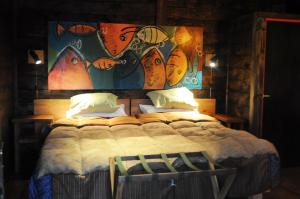 埃普延Las Pitras Lodge的卧室配有一张大床,墙上挂有绘画作品