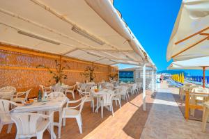 雷卡纳蒂港Residence I Giardini Del Conero的一间设有白色桌椅的餐厅以及海滩