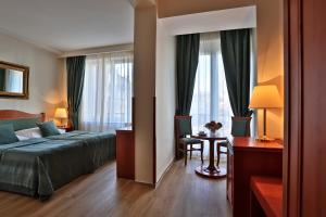 布拉格贝唯酒店的一间卧室配有一张床、一张书桌和一个窗户。