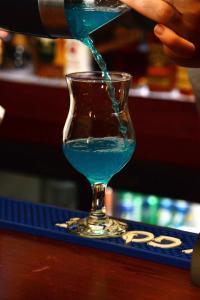 埃尔比勒菲奥里酒店的把一杯蓝色的饮料倒入玻璃杯中