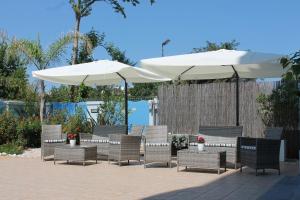 朱利亚诺瓦蓝色海洋公寓式酒店的庭院里摆放着一组椅子和遮阳伞