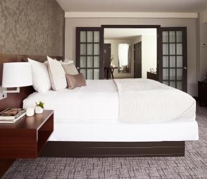 扬克斯皇家丽晶酒店的卧室配有一张白色的大床和一张桌子
