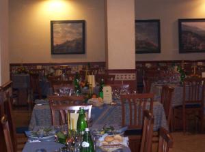 阿西西阿尔贝格拉罗卡酒店的用餐室配有桌椅和瓶子