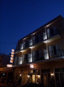 纳夫普利翁赫拉酒店的夜间带有 ⁇ 虹灯标志的酒店大楼