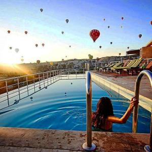 格雷梅Doors Of Cappadocia Special Cave Hotel的站在带热气球的游泳池中的女人