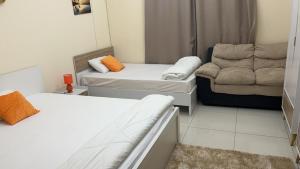 沙迦Deluxe Rooms in a shared apartment with Shared bathroom的一间小房间,配有两张床和一张沙发