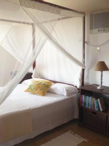 孔迪Pé na Areia的一间卧室配有一张带天蓬的白色床