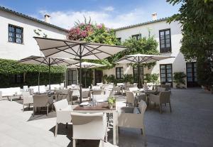 科尔多瓦柏丽奥宫酒店的一间设有白色桌椅和遮阳伞的餐厅