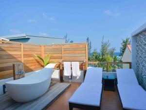 胡鲁马累呼尔胡维拉海滩椰子树酒店的阳台设有浴缸和甲板上的椅子