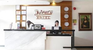 安吉利斯Devera Hotel的坐在桌子上的女人,坐在带时钟的房间