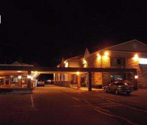 莱瑟姆Colonie Inn and Suites的夜间停在大楼前的汽车