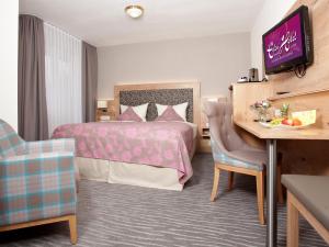 巴特克罗青根伊甸酒店的配有一张床和一张书桌的酒店客房