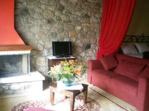 Graviá凯迪玛凯乐特斯塔公寓式酒店的客厅设有红色的沙发和石墙