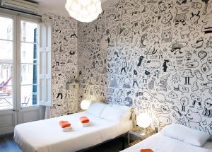 巴塞罗那ZOOROOMS Boutique Guesthouse的一张床铺,位于一个墙上涂有涂鸦的房间