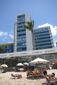 萨尔瓦多Apartamento Salvador VIP的一群人坐在海滩上,拿着遮阳伞